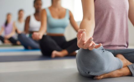 Close up of women group sit in lotus position with mudra hands meditate practice yoga at session. Girls have meditation class in fitness club, do sports workout train together. Healthy lifestyle.