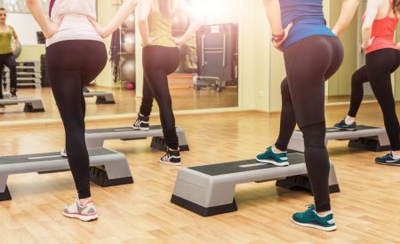 Group of women making step aerobics view from the backside